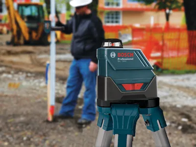 Bosch GRL 300 HV Professional laser level with person operating it at a construction site.