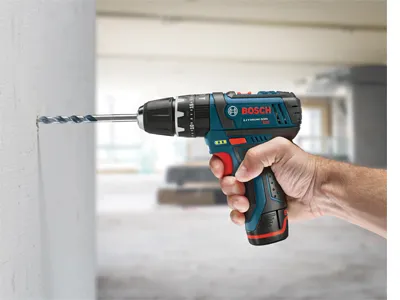 Bosch drill with "BOSCH" visible text, a drill bit is going through a white wall.
