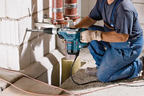 Worker using a Bosch hammer drill 11264EVS to drill into a concrete wall.