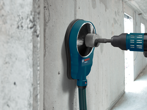 Bosch HDC250 concrete dust extraction hood attached to a drill, on a concrete wall.