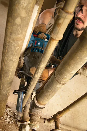 A person wearing work gloves using a RS 325 saw by to cut pipe.