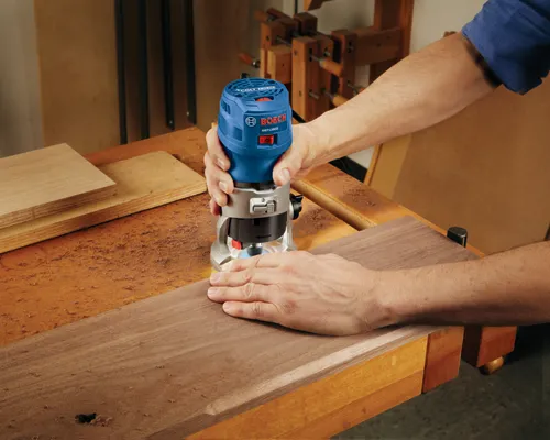 Bosch GKF125CE Colt 1.25 HP palm router being used on a piece of wood.