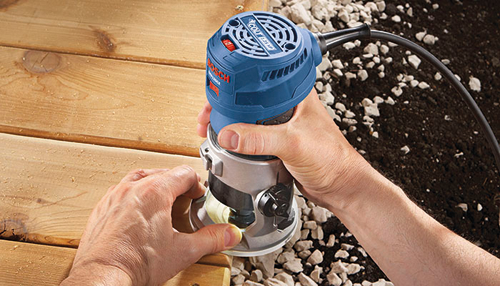 Bosch COLT 1.25 HP router, with operator using it to shape wood.