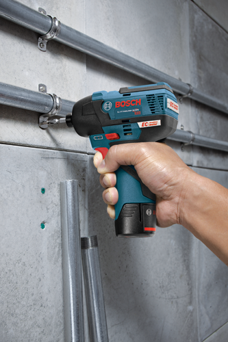 Bosch LITHIUM-ION 12V EC brushless motor impact driver, held in a hand, driving a screw into a bracket attached to a metal pipe on a concrete wall.
