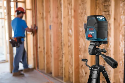 Bosch Professional GCL 2-160 laser level mounted on a tripod with a construction worker in the background.