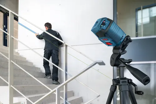Bosch Professional laser level, tripod, and a person walking up the stairs.
