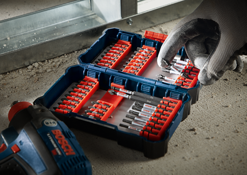 Bosch tool set with “BOSCH” labeled bits, a gloved hand picking up a bit, and a cordless drill with the "BOSCH" logo visible.