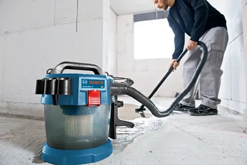Bosch GAS18V-3 vacuum cleaner, and person vacuuming the floor.