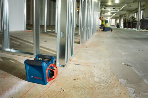 Bosch red and blue level, with a person working in a construction area.