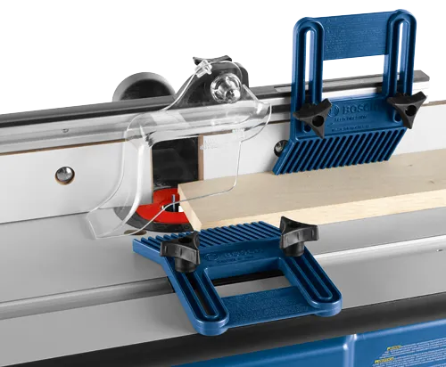 Bosch router table with blue safety guards, and wooden workpiece in progress.