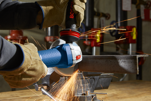 Bosch power tool cutting metal, generating sparks, held by gloved hands.