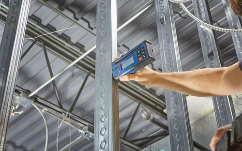 Bosch level tool in blue and black is used on a metal frame by a person, Bosch is visible on the tool.