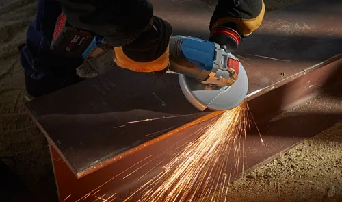 Person using a Bosch angle grinder to cut a metal beam; sparks fly from the cutting action.