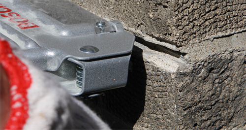 Bosch tool detail with red "BOSCH" text, next to a textured concrete surface. A gloved hand is visible.