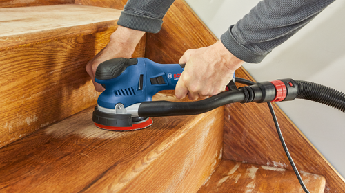 Bosch GETE sander being used on wooden stairs.