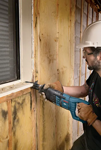 Man using a Bosch RS325 reciprocating saw to cut through a windowsill.