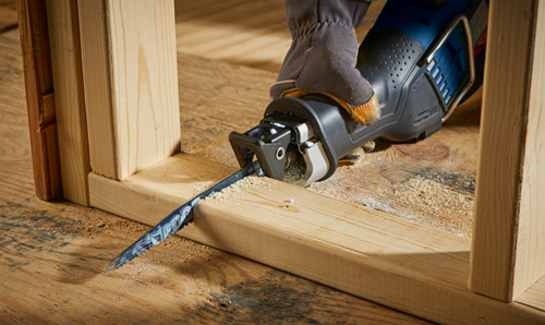 Bosch reciprocating saw cutting through a wooden frame, held by a person wearing a glove.