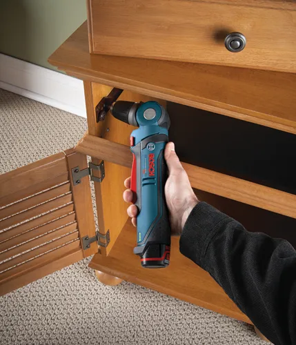 Bosch Lithium-ion drill being used to drill a hinge on a wooden cabinet.