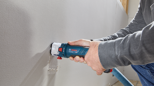 A person uses a Bosch GCU18V-30 oscillating tool on a drywall.