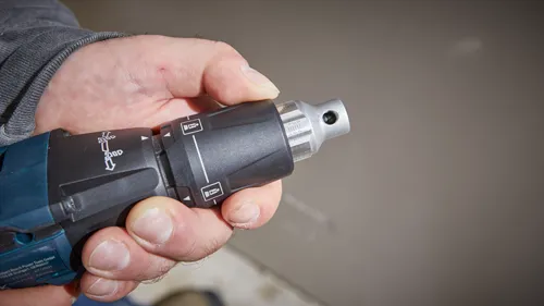 Hand holding a Bosch power drill with a directional arrow.