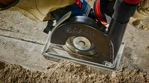 A BOSCH circular saw cutting into concrete, held by a gloved hand. The word “BOSCH” is visible on the saw guard.