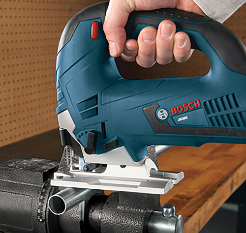 Bosch JS365 jigsaw cutting metal conduit in a workshop.