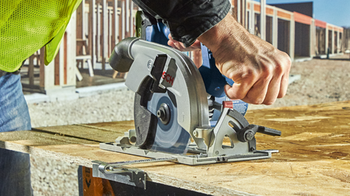 Bosch circular saw in use, visible on a wooden board. Worker in high visibility vest.