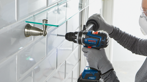 bosch diamond drill bit drilling into white tile in a bathroom with a glass shelf installed above