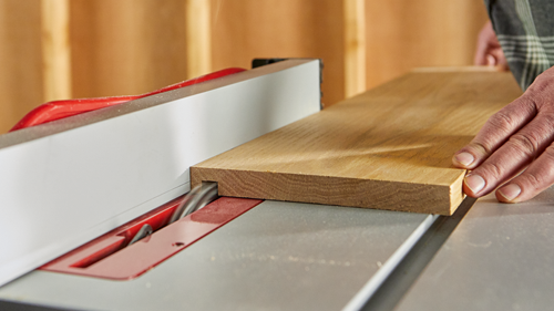 A person using a table saw to cut a piece of wood.
