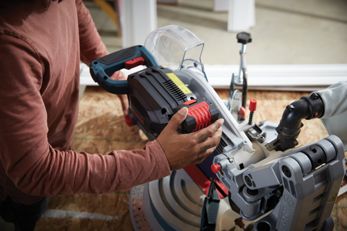 Person holding a Bosch miter saw.