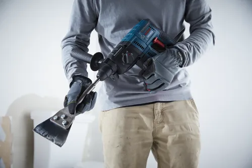 Person holding a Boschhammer GBH18V-21 rotary hammer and scraper.