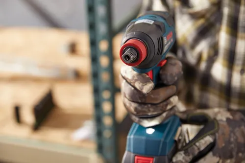 Bosch impact wrench held by a person wearing camouflage gloves.