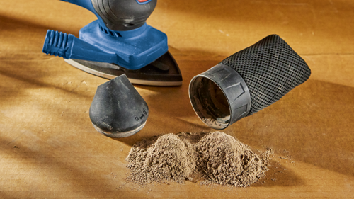 Bosch blue and black sander, with dust collection bag and pile of sawdust.