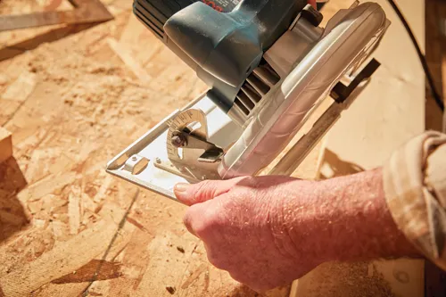 Bosch circular saw, held by a person, is in use on wood.