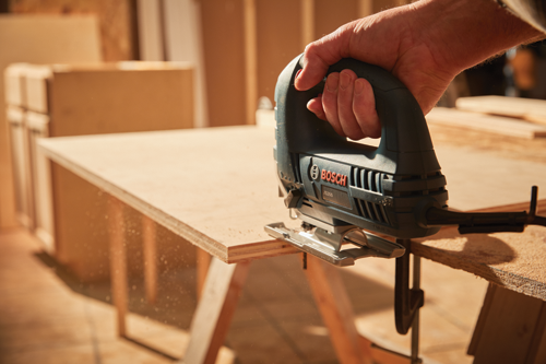 Man on a construction site using the Bosch jig saw to cut plywood.