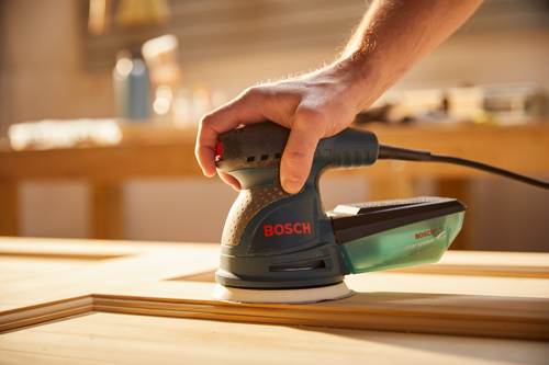 Bosch sander being used on a wood frame, visible text "BOSCH" and "microfilter system".