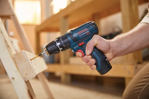 Bosch Lithium-Ion 12V drill being used to drive a screw into a wooden board.