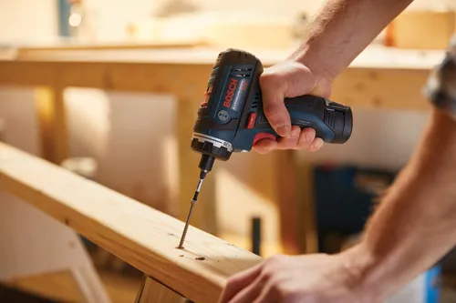 Bosch Lithium-Ion 12V cordless drill screwing a screw into a wooden plank.