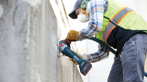 Person wearing protective gear and a safety vest using a Bosch GWX18V-10P grinder, “CORE18V.0Ah” battery.