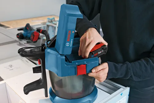 Bosch GAS18V-3 HD vacuum cleaner and CORE18V 4.0 Ah battery, person inserting battery.