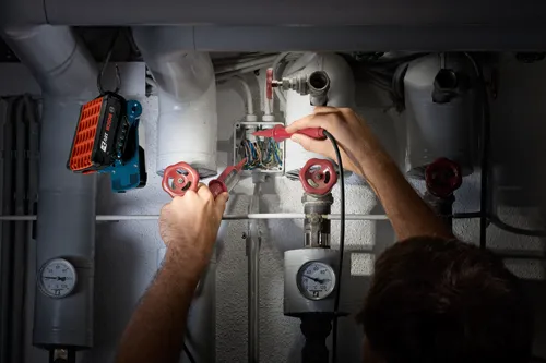 Man using the Bosch cordless worklight hanging from a hook to illuminate his work area.