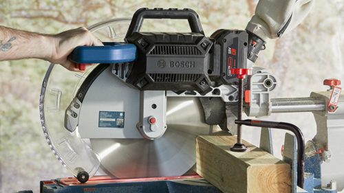 Bosch GCM18V-1250 12" (305mm) Miter Saw, with "AMP Share 18V 8 Ah" battery, a wood block, and a gloved hand.