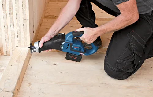 Bosch GSA18V-125 reciprocating saw, with 18V battery, being used by a person to cut a wooden beam.
