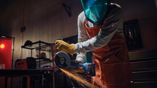 Person wearing protective gear using Bosch GWS18V-10P angle grinder, creating sparks.
