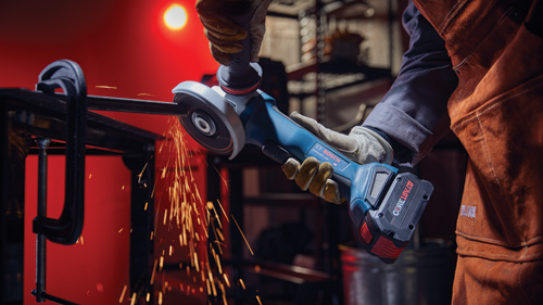 Bosch GWS18V-10P angle grinder cutting metal, with sparks flying, held by a person wearing gloves and safety attire.