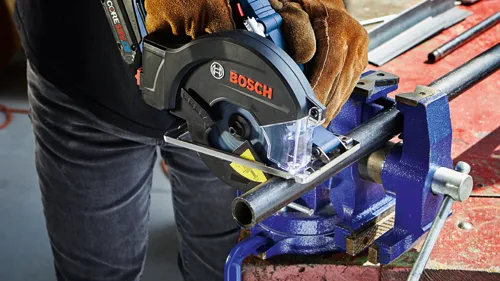 Bosch circular saw cutting a metal pipe secured in a vice.