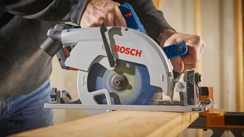 Bosch circular saw, with "BOSCH" logo and "18V" printed on the saw, cutting a wooden board.