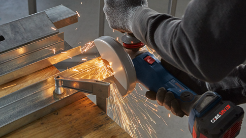 Person using a Bosch GWS18V-125C angle grinder to cut metal, with sparks flying.