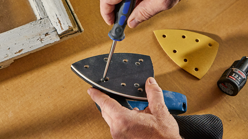 Hands holding a screwdriver, working on a sander with a yellow sanding pad and a 12 V 2.0 Ah Li-ion Bosch battery.