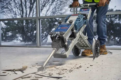 Bosch hammer, Bosch logo visible, person using it to break tiles on a floor.